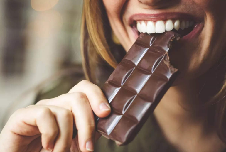 Woman eating a bar of chocolate. Concept for benefits of eating Mushroom Chocolate Bars