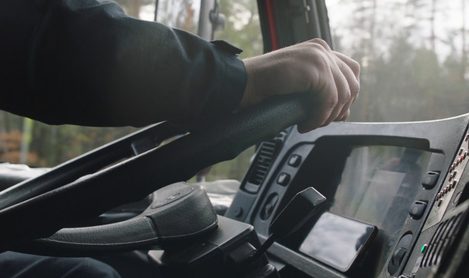 A truck driver holding his hands on a steering wheel